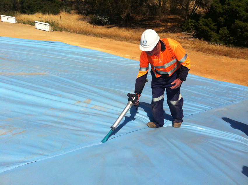 Step 2: Sewn PPE tarpaulin seam being sealed with Global TarpSeal RB using a cordless mastic application gun
